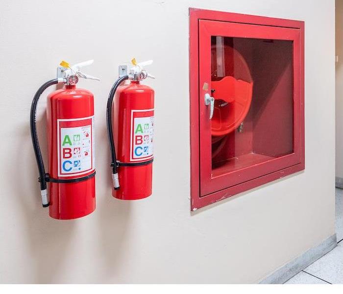 Two red fire extinguishers hanging on the wall in a commercial building.